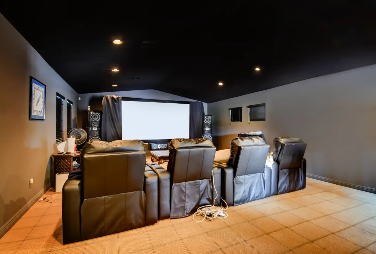 Upstairs game room set up as a home theater with tiered recliners and a projection screen